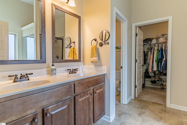 full bathroom featuring toilet, double vanity, baseboards, and a sink