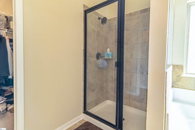 bathroom with a shower stall, a spacious closet, and baseboards