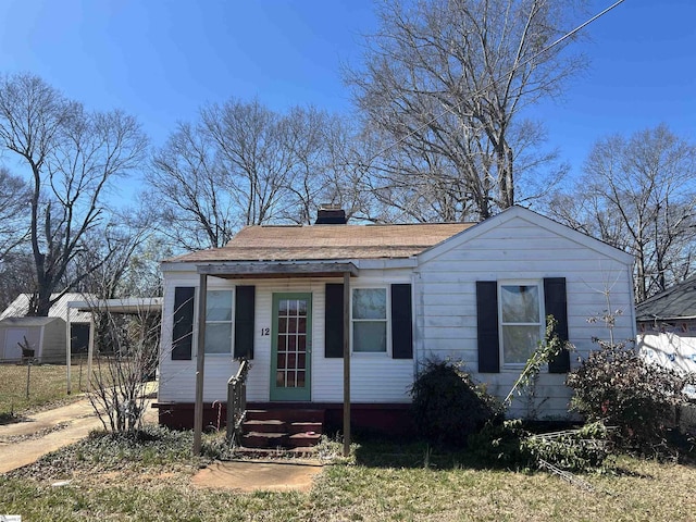 bungalow-style home with entry steps, driveway, and a chimney