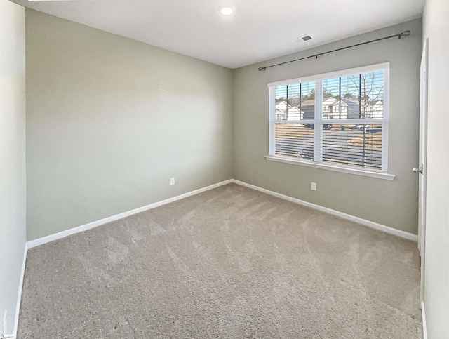 carpeted spare room with visible vents and baseboards