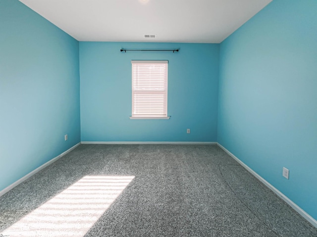 carpeted spare room featuring visible vents and baseboards