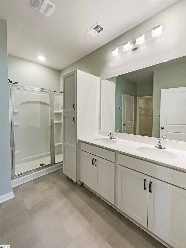 bathroom featuring double vanity, a stall shower, a sink, and visible vents