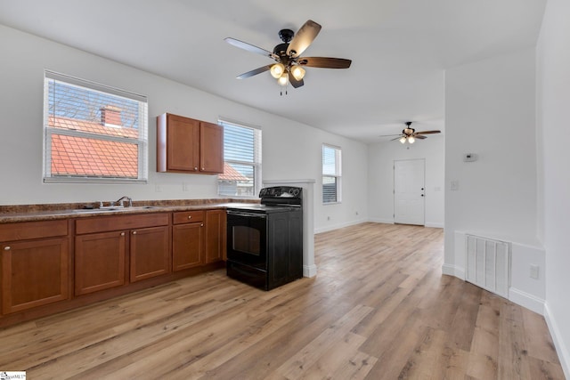 kitchen with a sink, visible vents, light wood-style floors, black electric range, and brown cabinetry