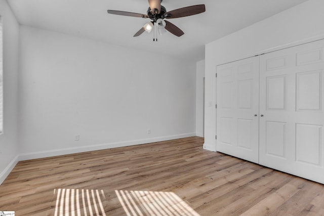 unfurnished bedroom featuring a ceiling fan, light wood-type flooring, a closet, and baseboards