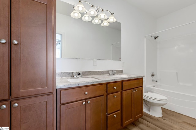 full bathroom featuring wood finished floors, double vanity, bathtub / shower combination, and a sink