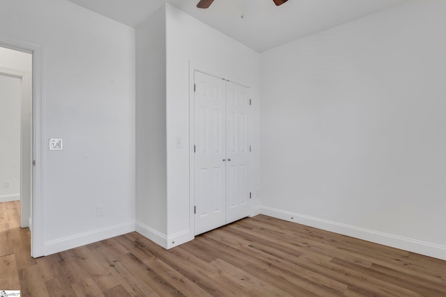 unfurnished bedroom with a closet, wood finished floors, and baseboards