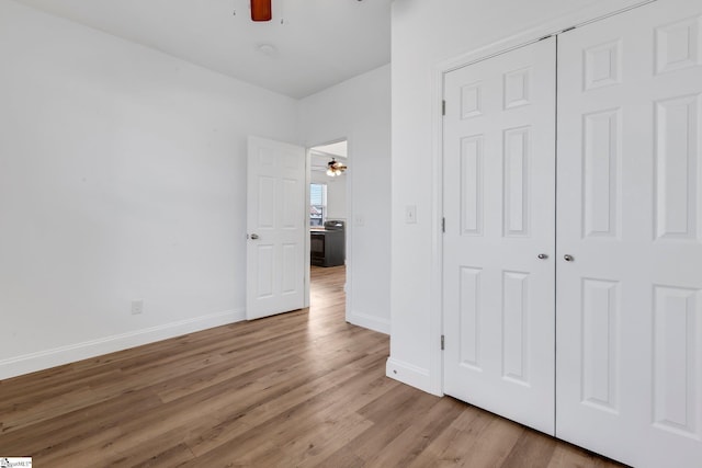 unfurnished bedroom with baseboards, a closet, a ceiling fan, and light wood-style floors