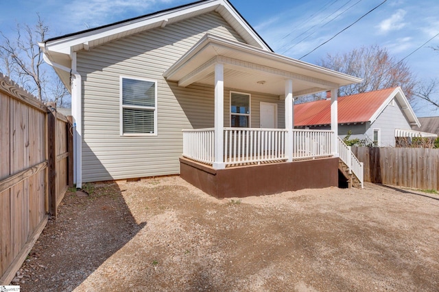 rear view of property with a porch, crawl space, and fence