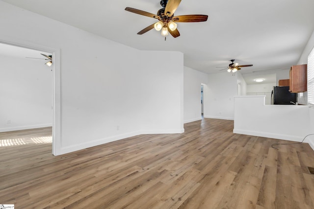 unfurnished living room with ceiling fan, light wood-type flooring, and baseboards