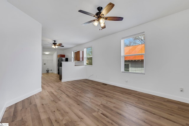 unfurnished living room featuring light wood-type flooring, ceiling fan, and baseboards