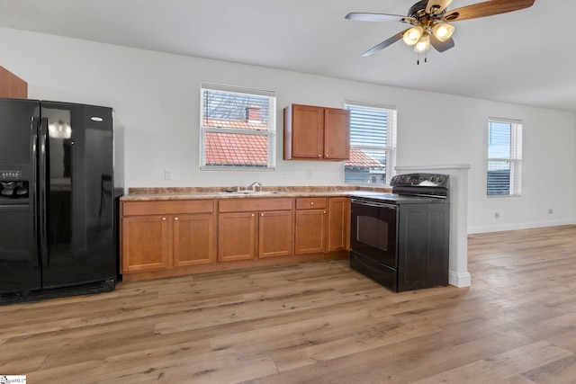 kitchen with light wood-style floors, brown cabinets, a sink, and black appliances