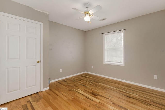 spare room featuring ceiling fan, light wood-style flooring, visible vents, and baseboards