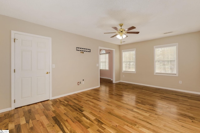 spare room with a ceiling fan, baseboards, visible vents, and light wood finished floors