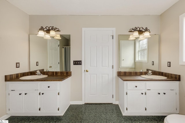 bathroom with two vanities, a sink, and baseboards