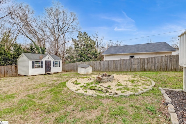 view of yard featuring a fenced backyard, a fire pit, and an outbuilding