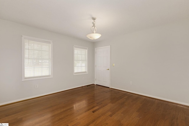 unfurnished room with dark wood-type flooring and baseboards