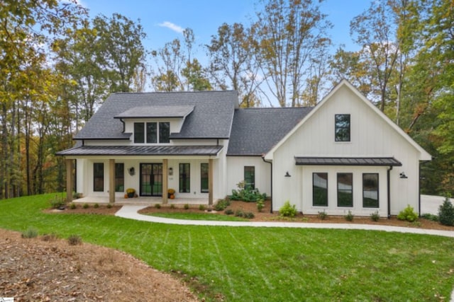 modern farmhouse style home featuring metal roof, covered porch, a shingled roof, a front lawn, and a standing seam roof