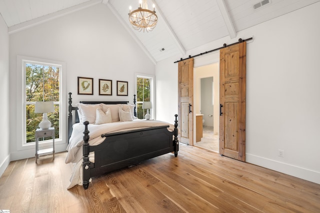 bedroom featuring a barn door, visible vents, light wood-style floors, high vaulted ceiling, and beam ceiling