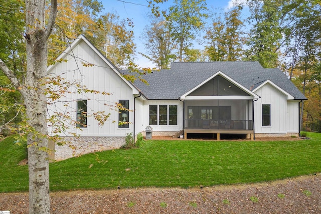 back of house featuring a sunroom, a lawn, and roof with shingles