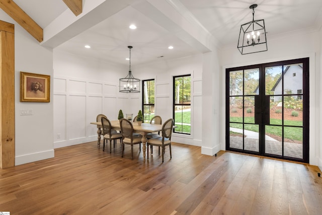 dining room with french doors, beam ceiling, a decorative wall, an inviting chandelier, and light wood-type flooring