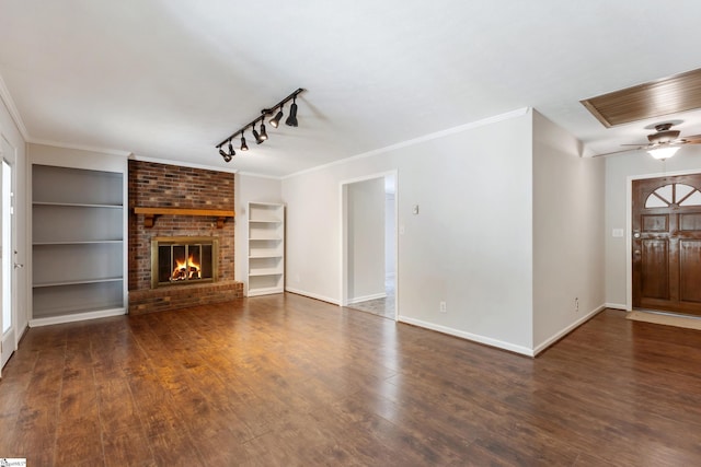 unfurnished living room with built in shelves, a brick fireplace, baseboards, and wood finished floors