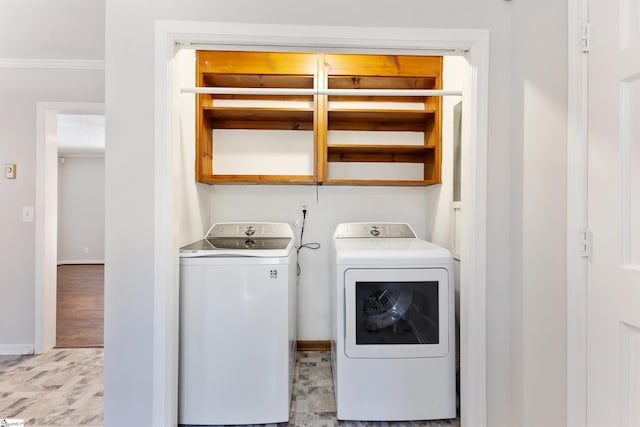 clothes washing area featuring laundry area, baseboards, ornamental molding, wood finished floors, and washing machine and clothes dryer