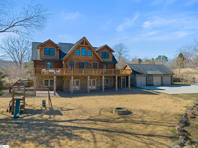 view of front of home featuring an outbuilding, a front yard, stone siding, a fire pit, and a wooden deck