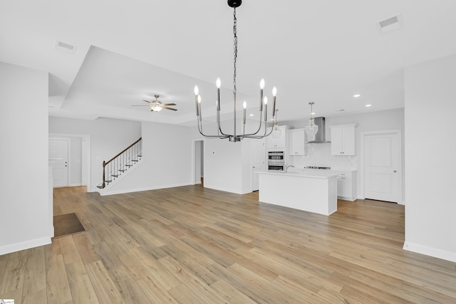 kitchen with light wood-type flooring, wall chimney exhaust hood, visible vents, and open floor plan