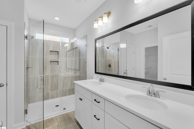 bathroom featuring double vanity, a stall shower, and a sink