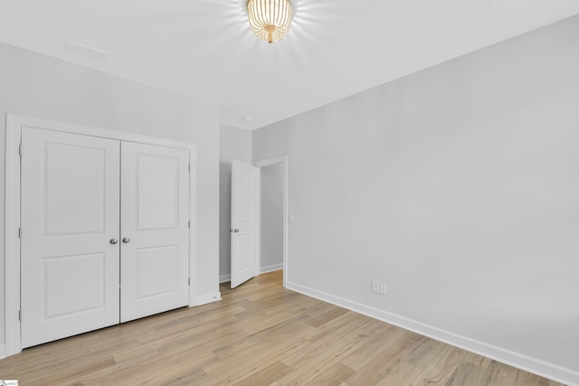 unfurnished bedroom featuring a closet, light wood-style flooring, and baseboards