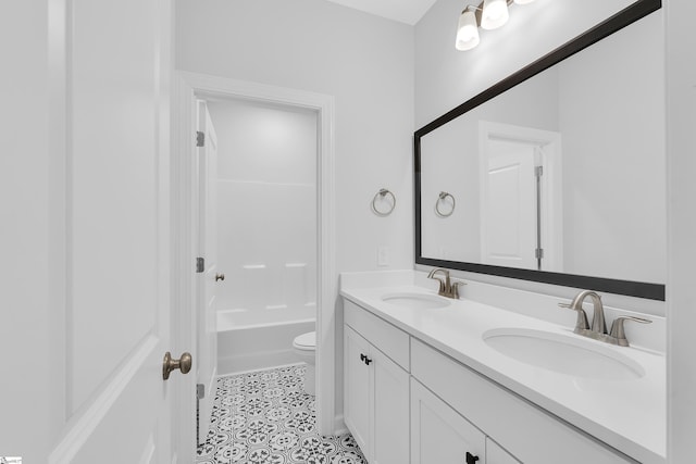 bathroom with double vanity, a sink, toilet, and tile patterned floors