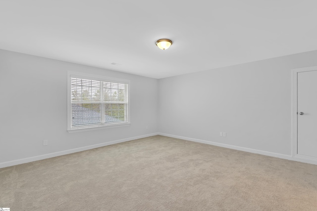 unfurnished room with light carpet and baseboards