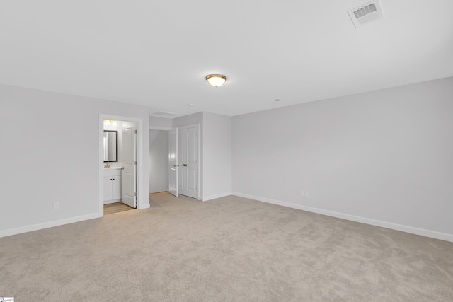 unfurnished bedroom featuring baseboards, visible vents, connected bathroom, and light colored carpet