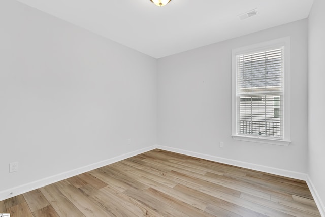 empty room featuring visible vents, baseboards, and wood finished floors