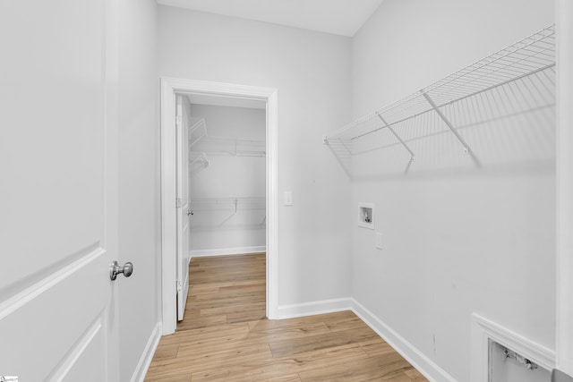 washroom featuring laundry area, washer hookup, light wood-style flooring, and baseboards