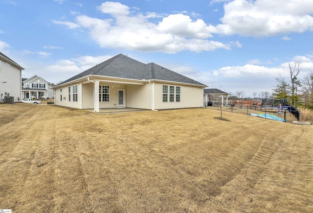 rear view of property with cooling unit, fence, a lawn, a trampoline, and a patio area