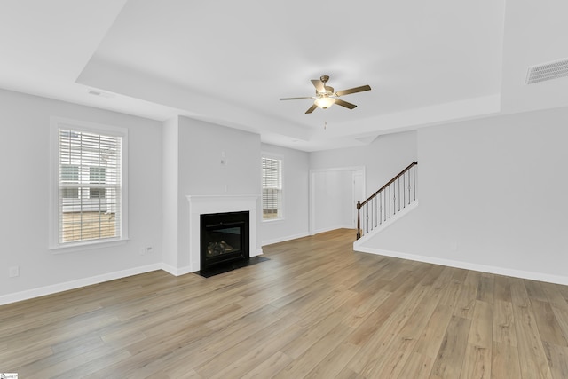 unfurnished living room featuring a healthy amount of sunlight, light wood-style floors, and stairs