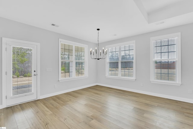 unfurnished dining area featuring a healthy amount of sunlight, light wood-style flooring, visible vents, and a notable chandelier