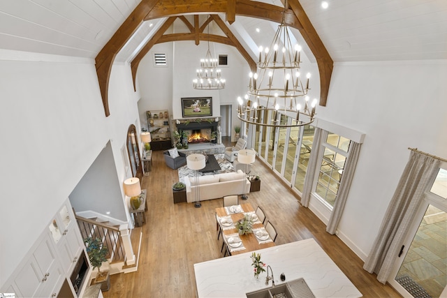 living area featuring visible vents, a stone fireplace, wood finished floors, high vaulted ceiling, and stairs