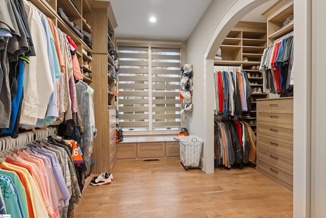 spacious closet featuring arched walkways and light wood finished floors