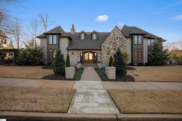 french country home featuring stone siding, french doors, and a chimney