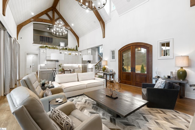 living area with a chandelier, arched walkways, stairs, french doors, and light wood-type flooring