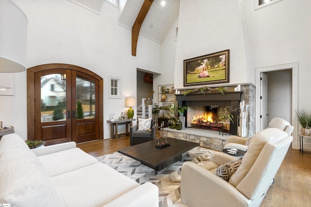 living area with light wood-style floors, stairs, french doors, and a stone fireplace