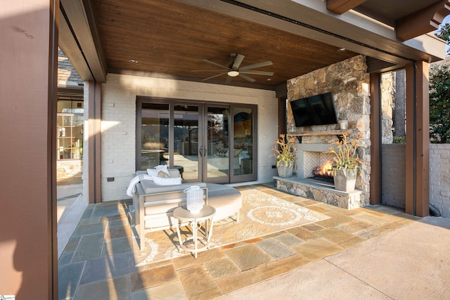 view of patio / terrace with french doors, an outdoor stone fireplace, and a ceiling fan