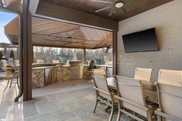 view of patio / terrace with a ceiling fan, area for grilling, a grill, outdoor wet bar, and outdoor dining space