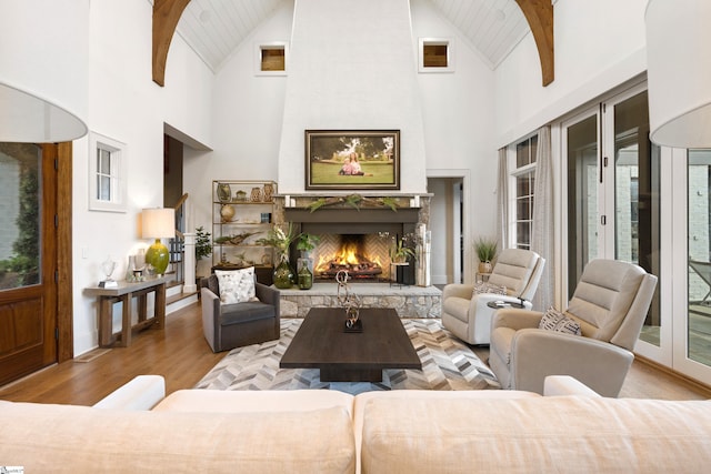 living room with beamed ceiling, a premium fireplace, plenty of natural light, and wood finished floors