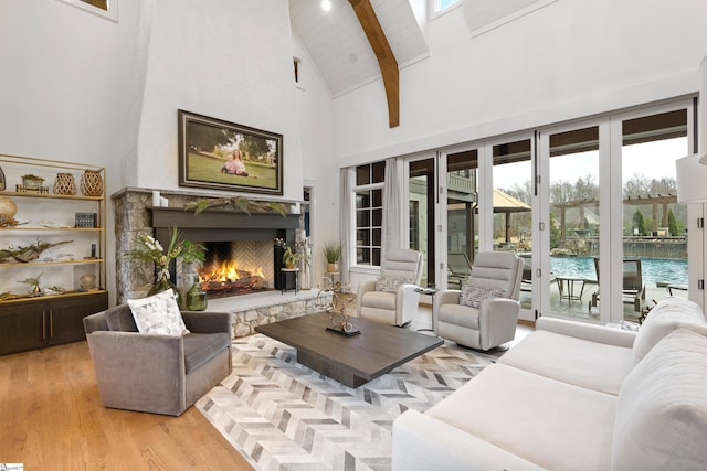 living area featuring wooden ceiling, beamed ceiling, wood finished floors, high vaulted ceiling, and a high end fireplace