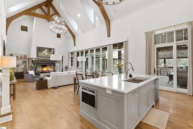 kitchen with high vaulted ceiling, a fireplace, a sink, light countertops, and light wood-type flooring