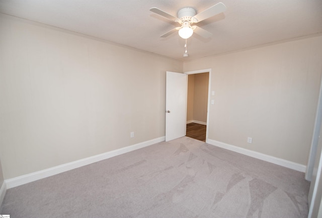 spare room with light carpet, ceiling fan, and baseboards