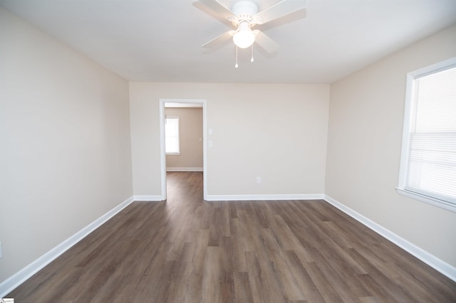 spare room featuring a ceiling fan, dark wood-style flooring, and baseboards